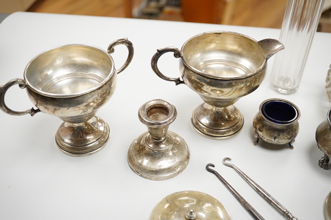 An early 20th century silver mounted cut glass scent bottle, five silver mounted glass toilet jars, a pair of silver mounted dwarf candlesticks, two silver condiments, a sterling jug(weighted), a sterling cup and cover(w
